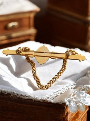 Broche vintage dorée à chaîne, perle centrale, bijou fantaisie rétro élégant