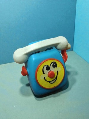 Téléphone jouet vintage Tomy 1978 bleu à remontoir, visage souriant rétro