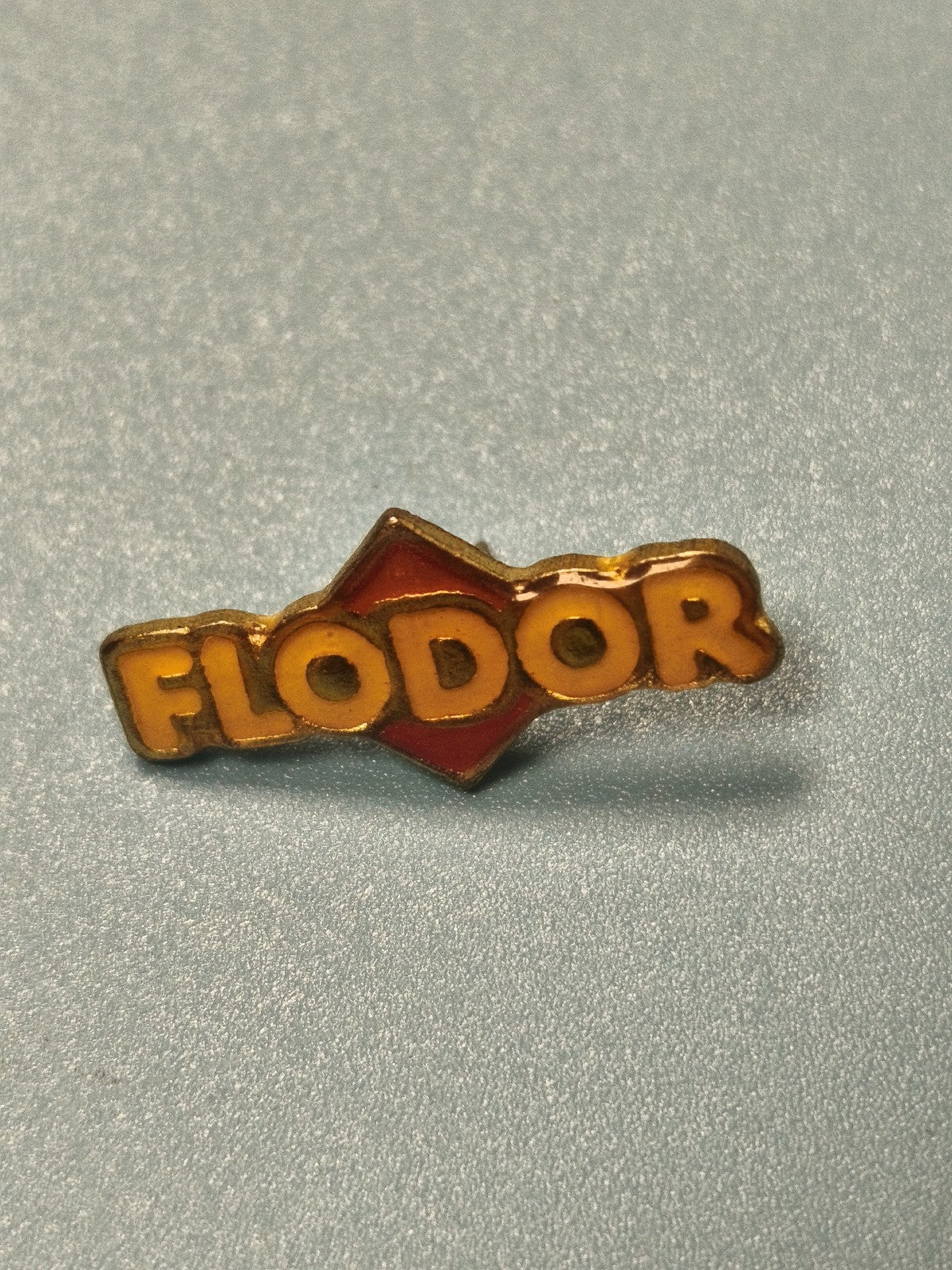 Pin's vintage Flodor logo jaune et rouge collection publicitaire ancien