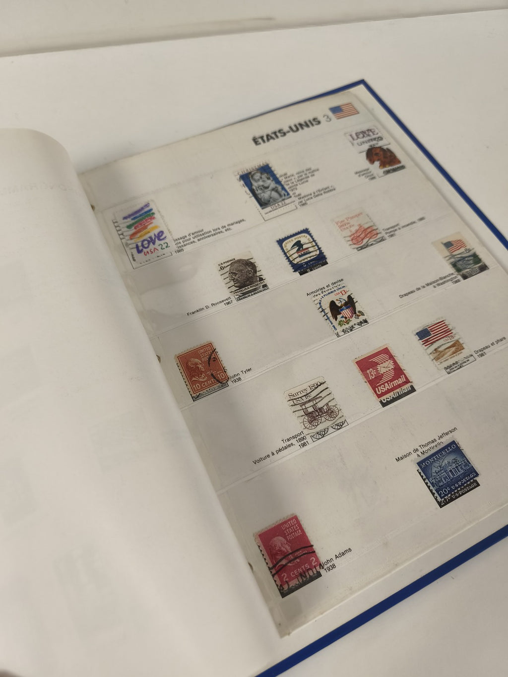 Classeur de timbres partiellement rempli, pages thématiques, couverture bleue