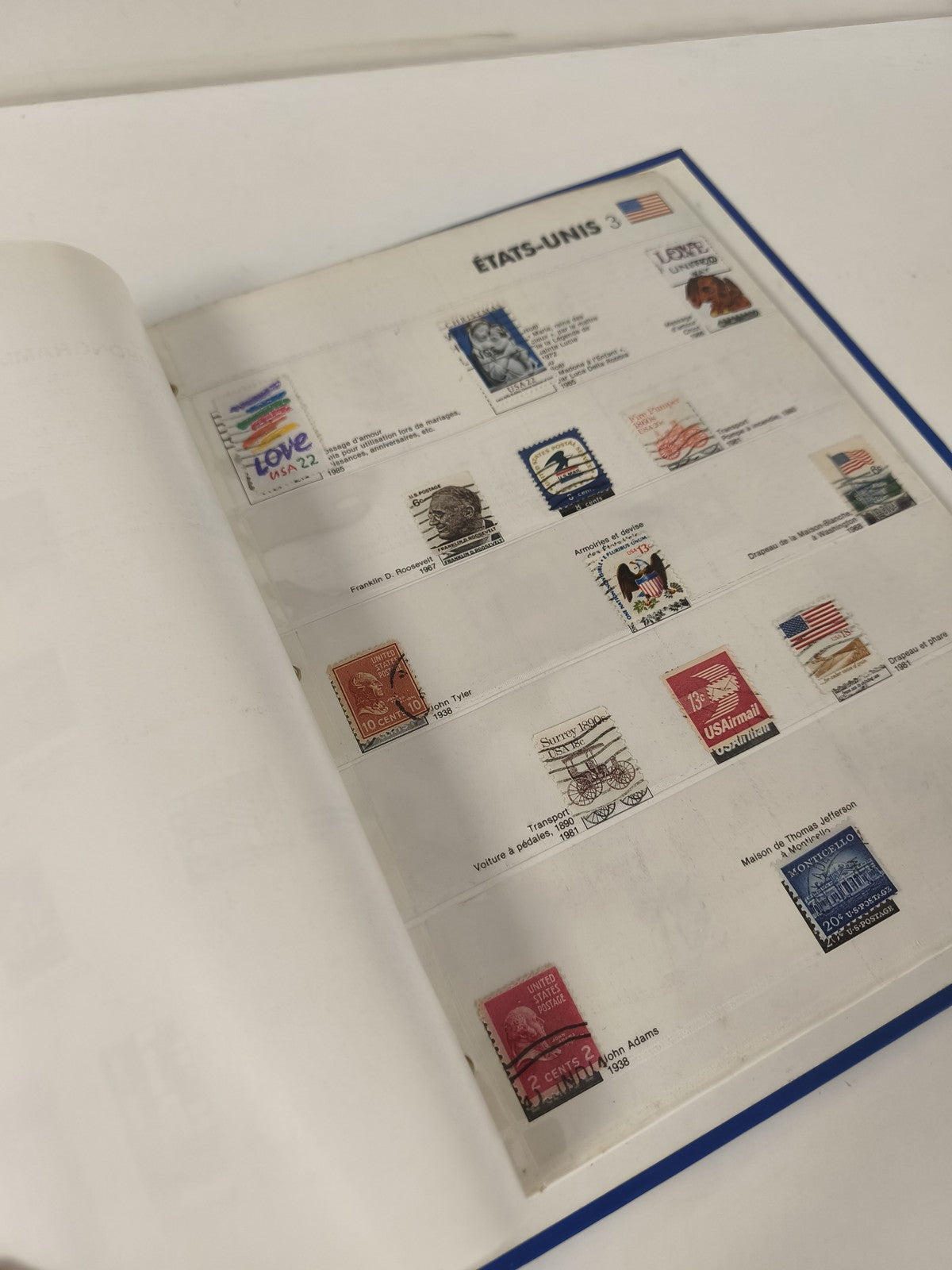 Classeur de timbres partiellement rempli, pages thématiques, couverture bleue