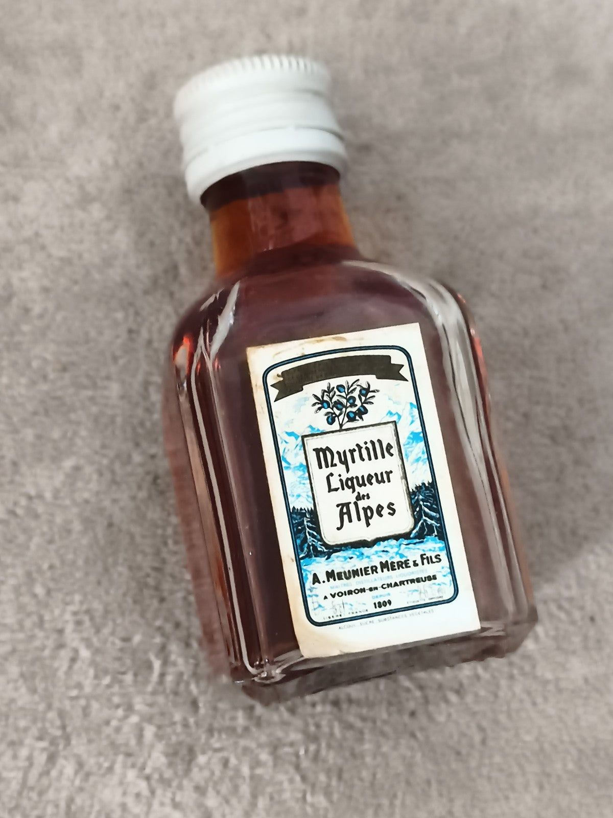 Mini-bouteille Myrtille Liqueur des Alpes A. Meunier Fils partiellement remplie