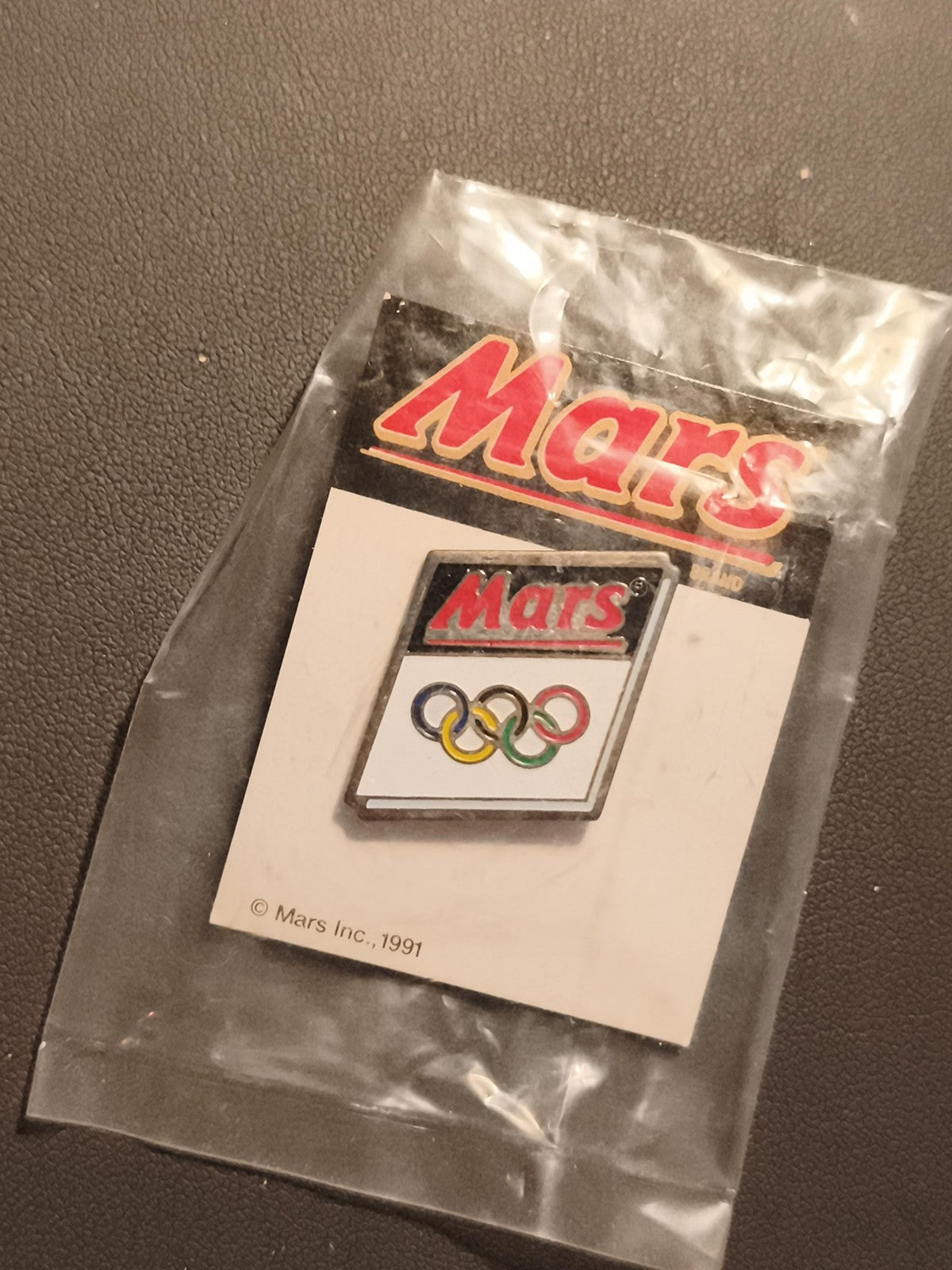 Pin's Mars Jeux Olympiques 1991 logo anneaux olympiques sous blister