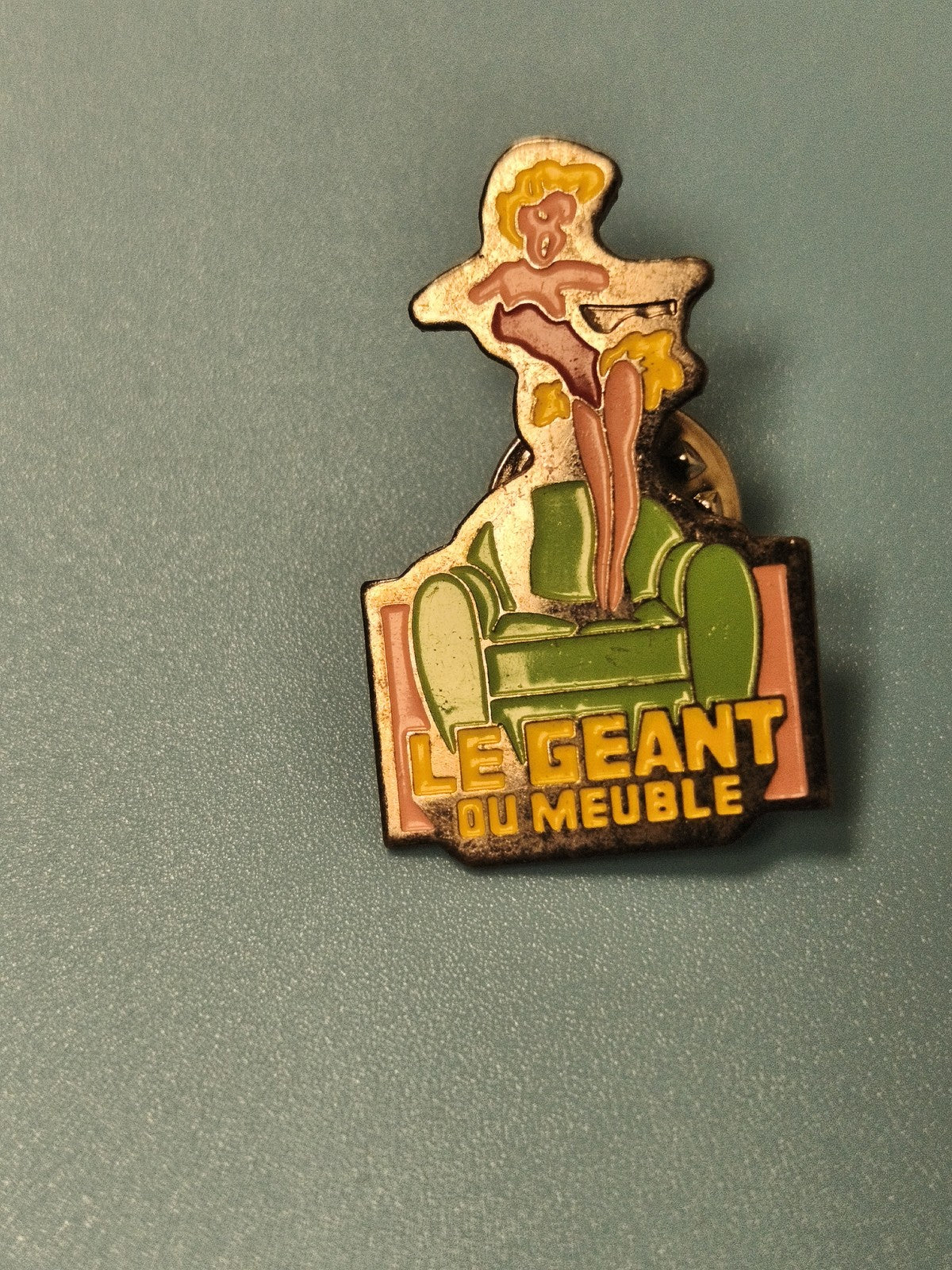 Pin's vintage Le Géant du Meuble publicitaire, femme stylisée, canapé vert