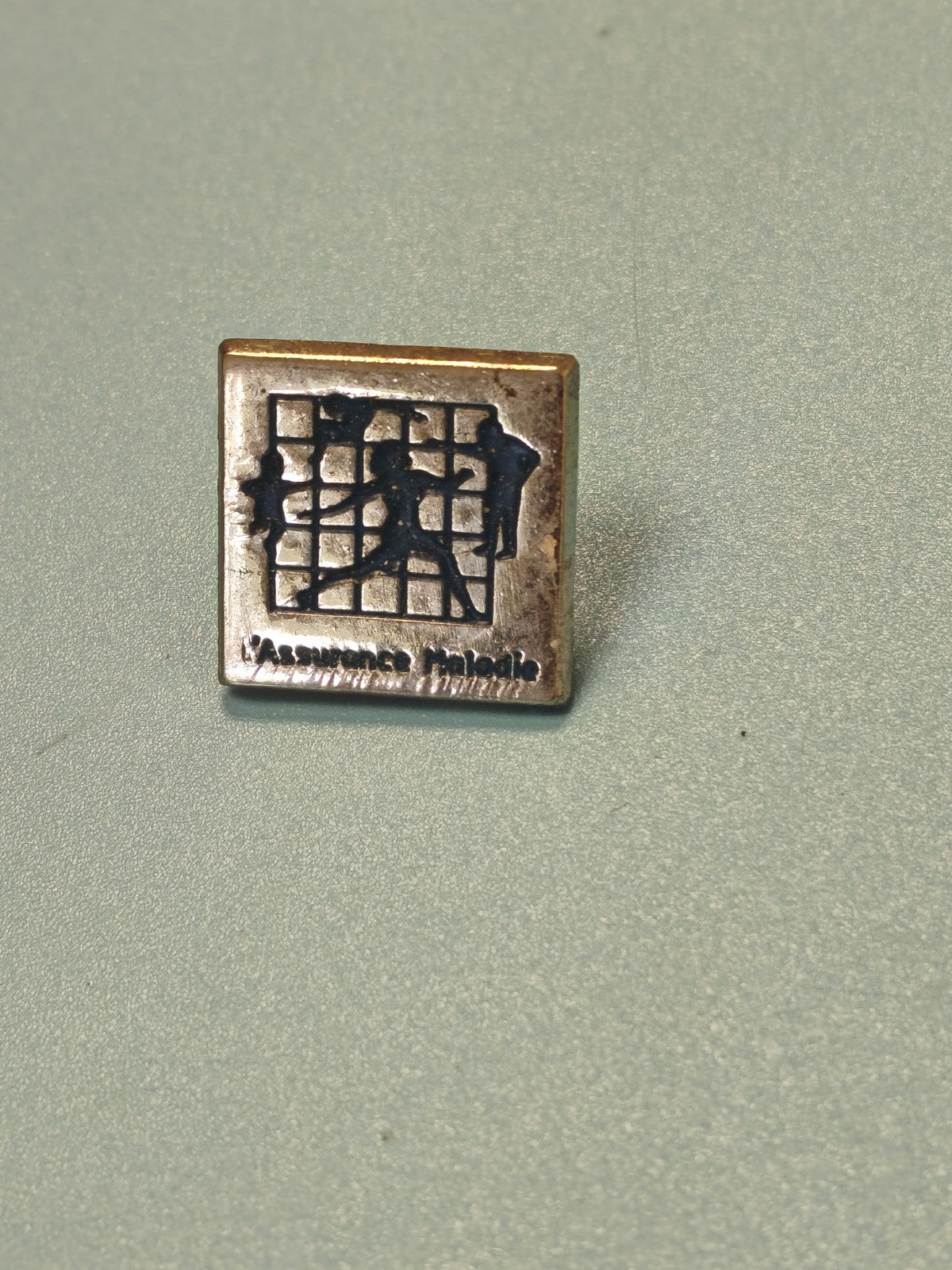Vintage pin's Assurance Maladie carré, logo silhouettes, collection santé