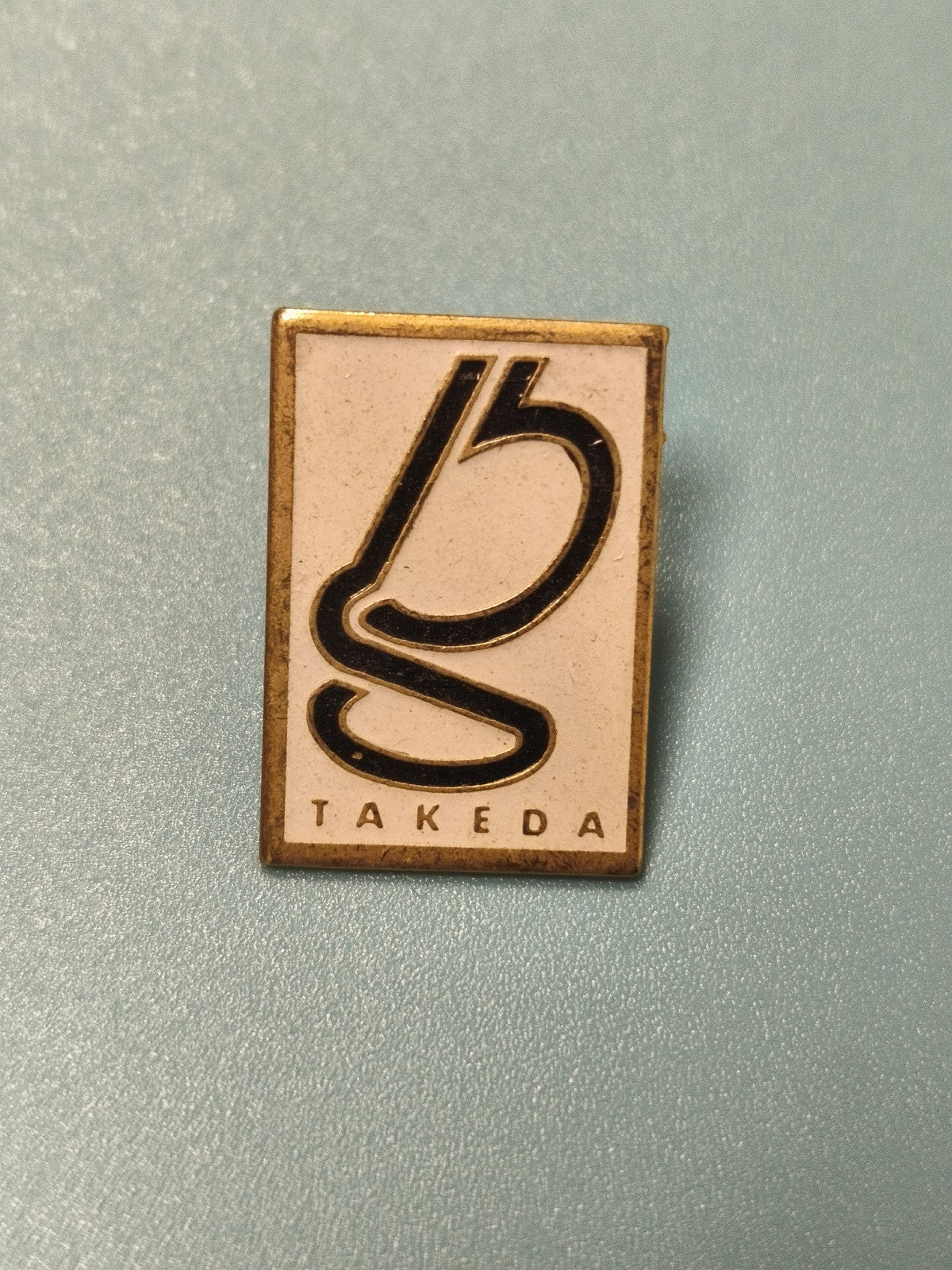 Pin's vintage Takeda rectangulaire logo noir et doré collection rare