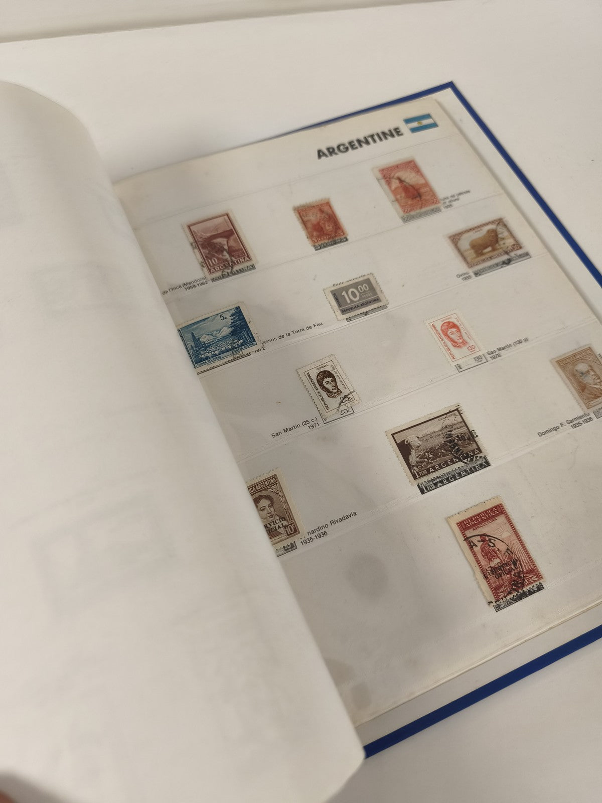 Classeur de timbres partiellement rempli, pages thématiques, couverture bleue
