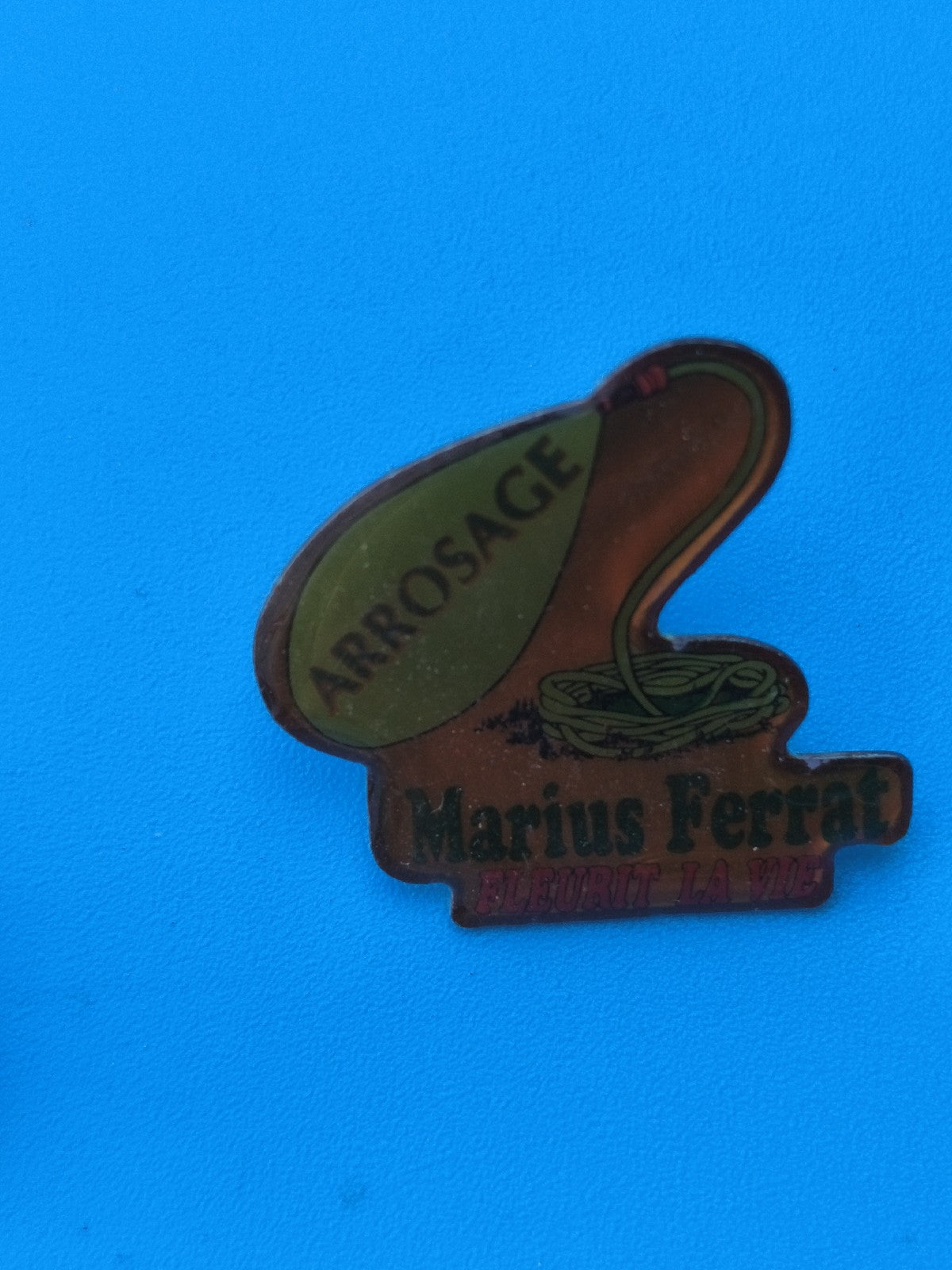 Vintage pin's Marius Ferrat arrosage publicitaire ancien jardin (Ref 8)