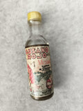 Mini-bouteille Mezcal Gusano Rojo partiellement remplie étiquette Oaxaca