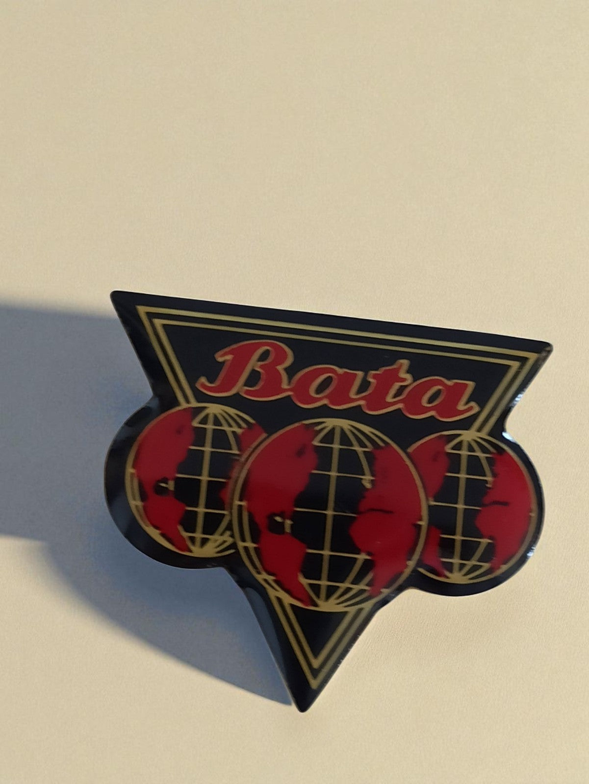 Pin's publicitaire vintage Bata logo globe triangle, badge ancien rare