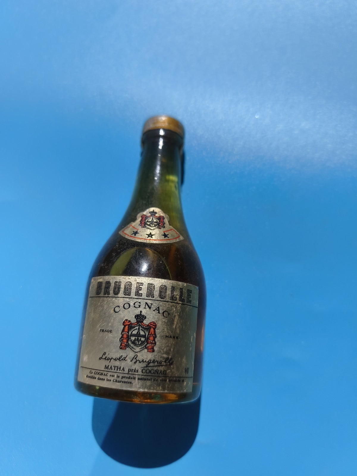 Mignonnette vintage Brugerolle Cognac ancienne, bouteille alcool mi-pleine colle