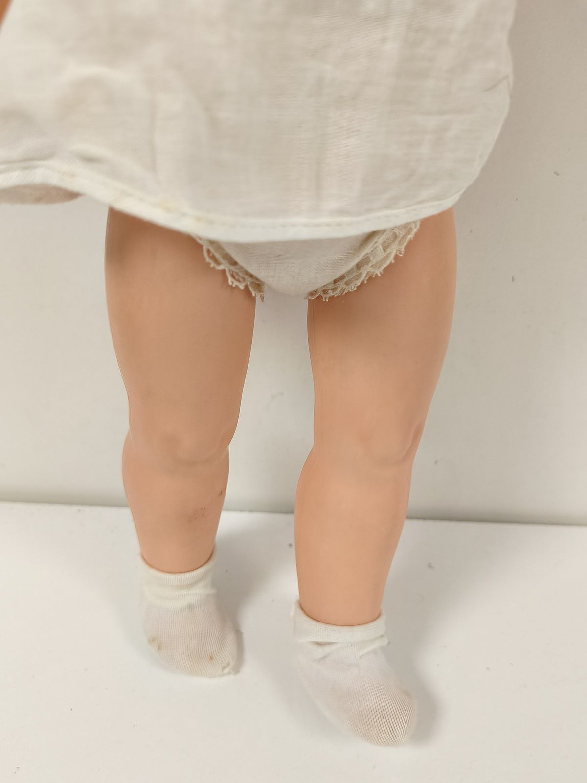 Ancienne poupée blonde aux yeux bleus, robe blanche et corps articulé