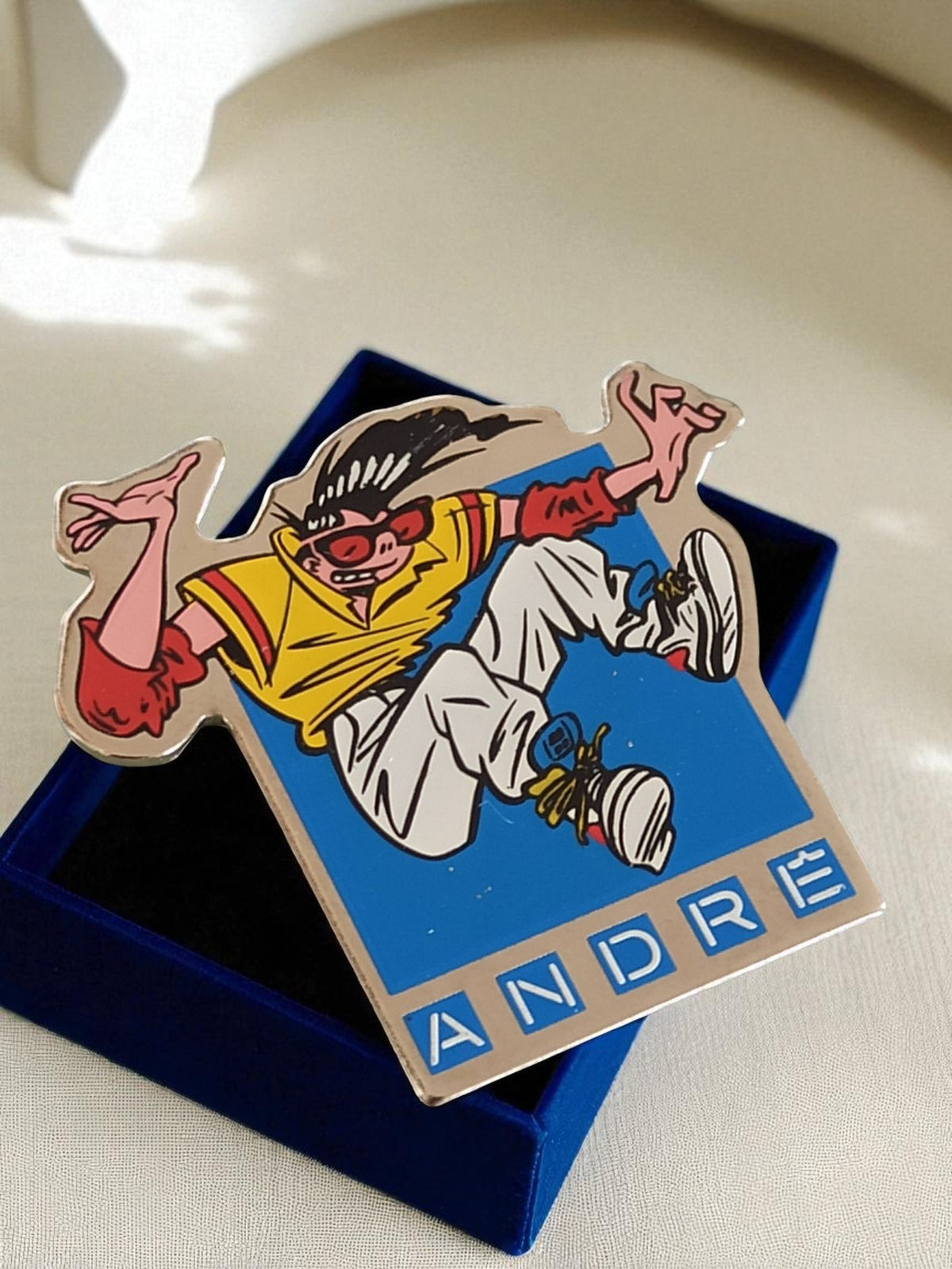 Vintage ANDRÉ advertising pin from the 90s, comic book style, colorful enamel badge