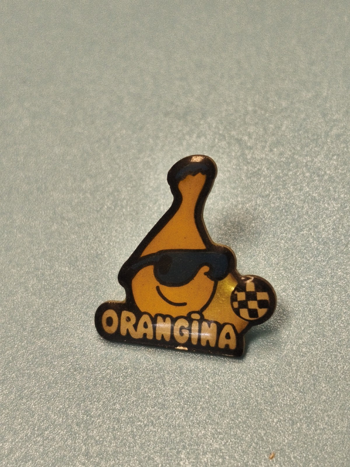 Vintage pin's Orangina logo bouteille jaune lunettes, objet publicitaire rétro