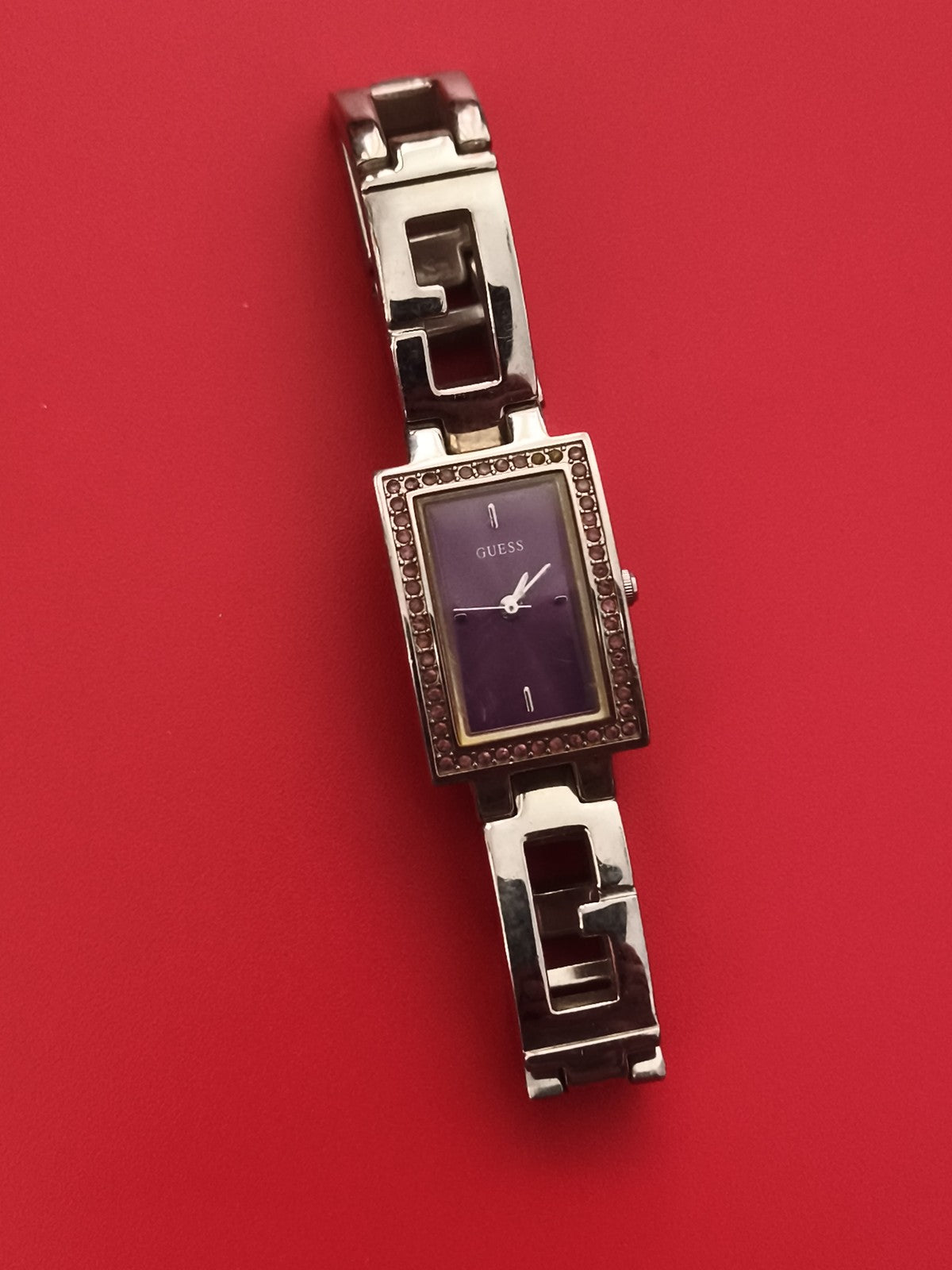 Montre femme Guess bracelet G argenté cadran violet strass rectangulaire