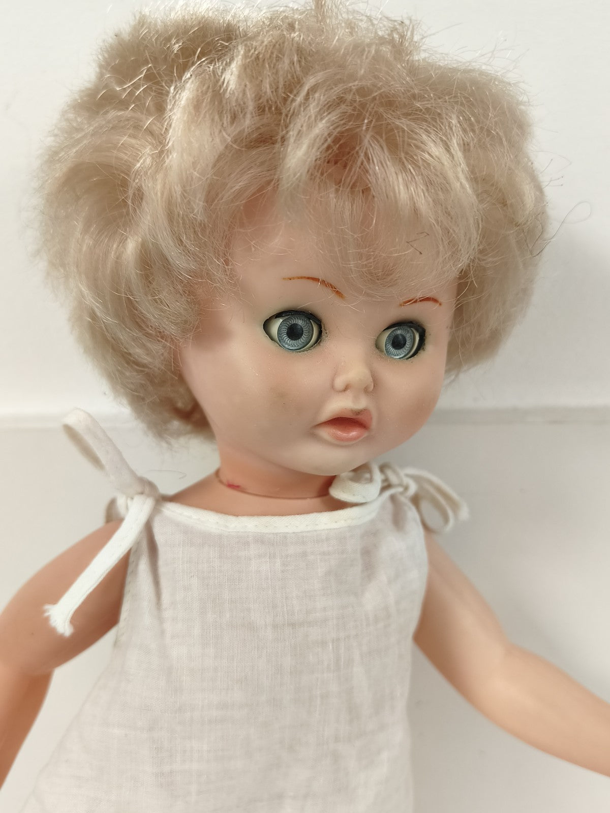Ancienne poupée blonde aux yeux bleus, robe blanche et corps articulé