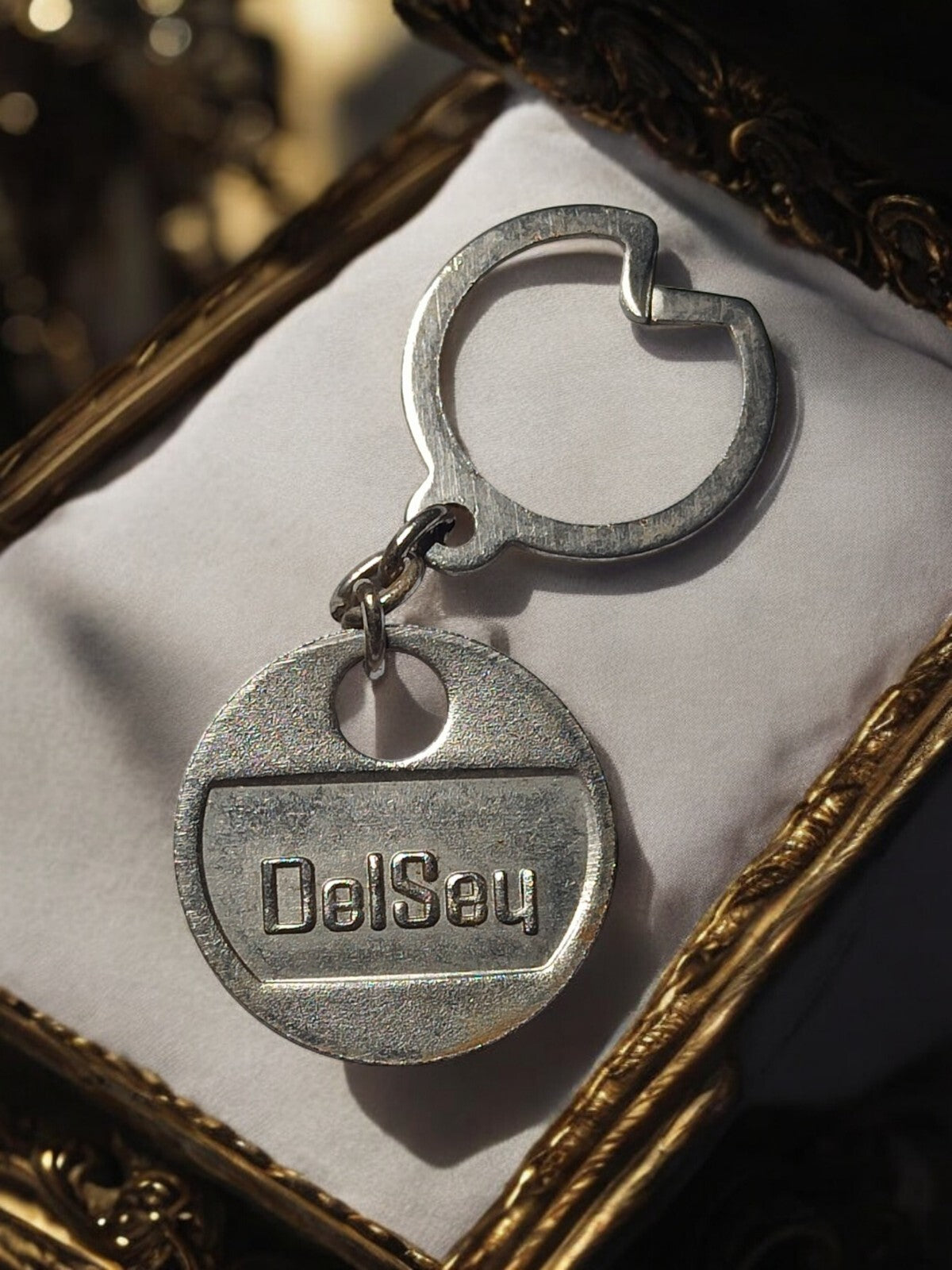 Porte-clés Delsey vintage en métal argenté logo relief, accessoire rétro