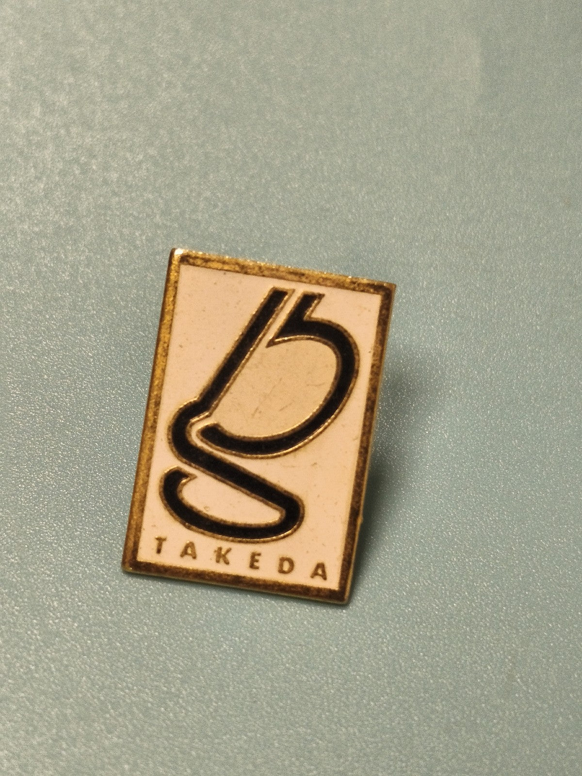 Vintage pin's Takeda rectangulaire logo noir sur fond blanc collection