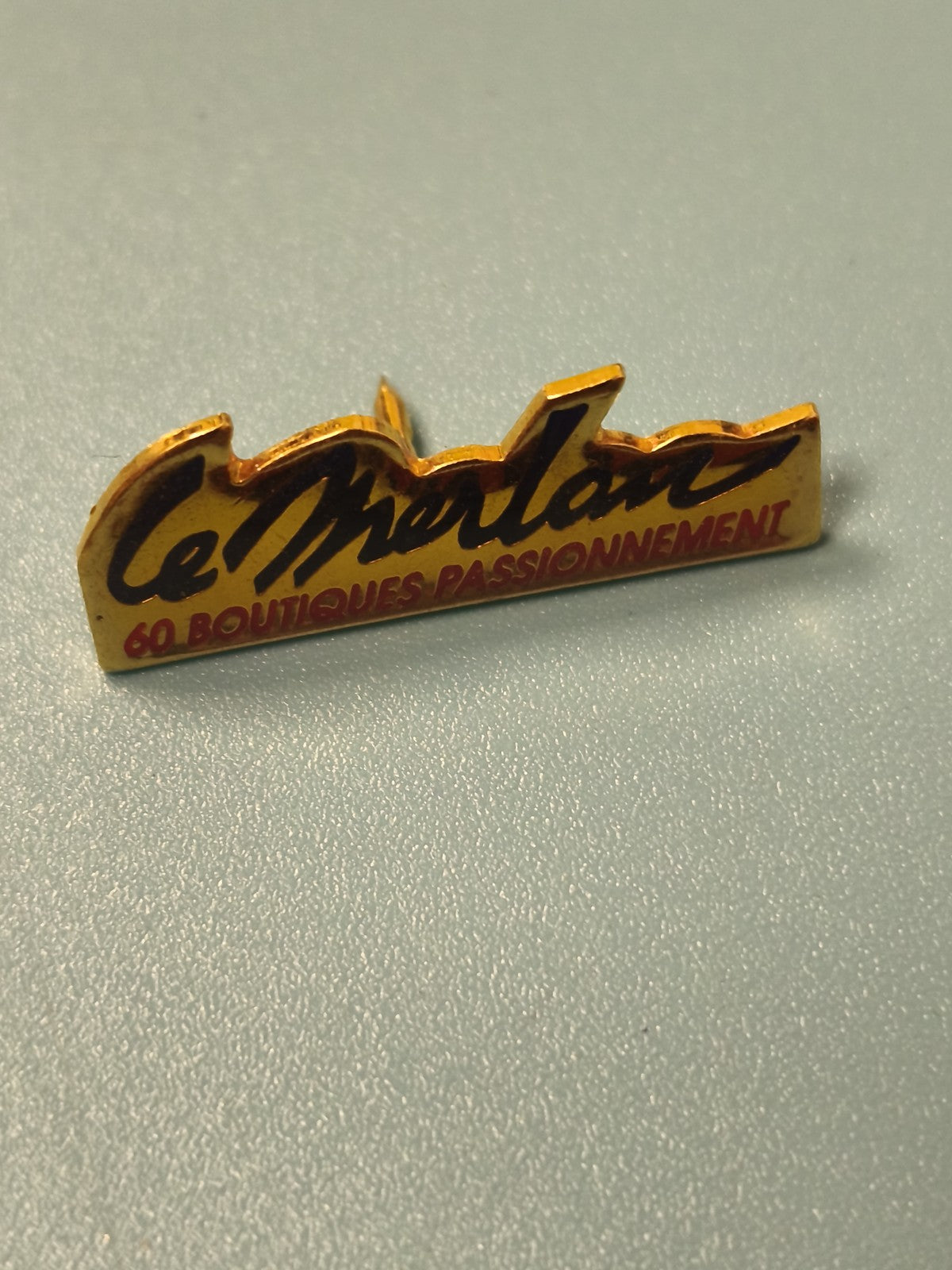 Vintage pin's publicitaire Le Merlan 60 boutiques passionnément jaune noir (Ref