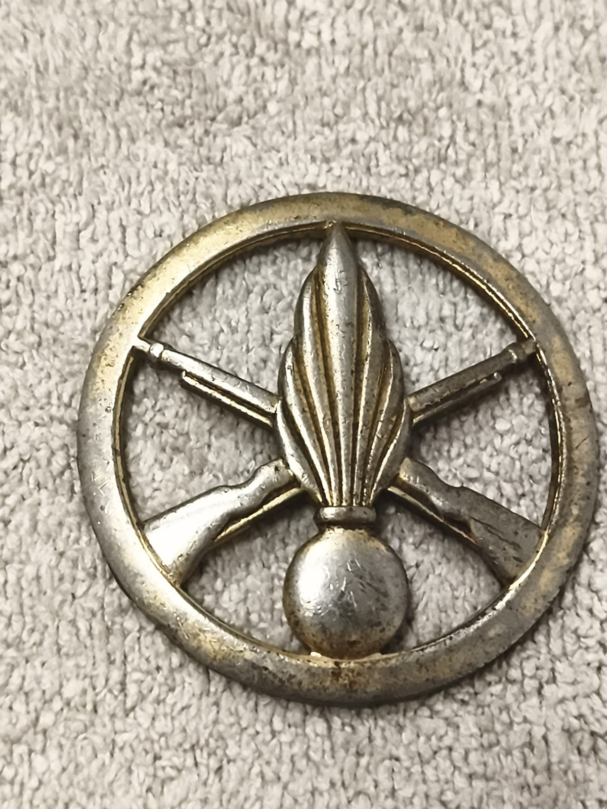 Ancienne médaille insigne militaire, grenade et fusils croisés, aspect métal pat