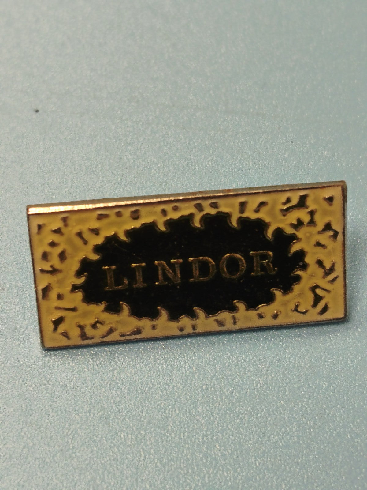 Vintage pin's Lindor rectangulaire noir et doré collection publicitaire
