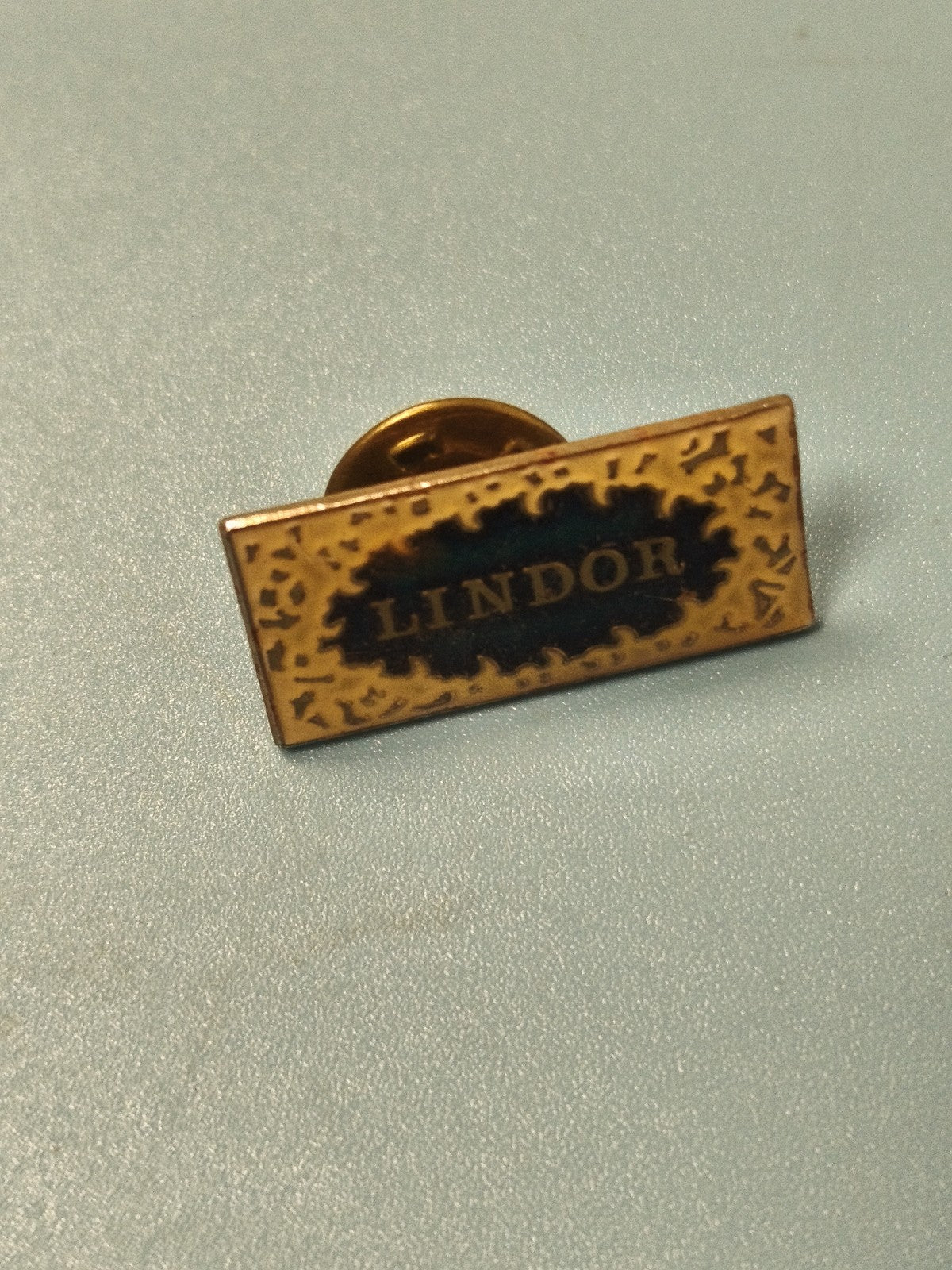 Vintage pin's Lindor rectangulaire doré émaillé collection publicitaire rare