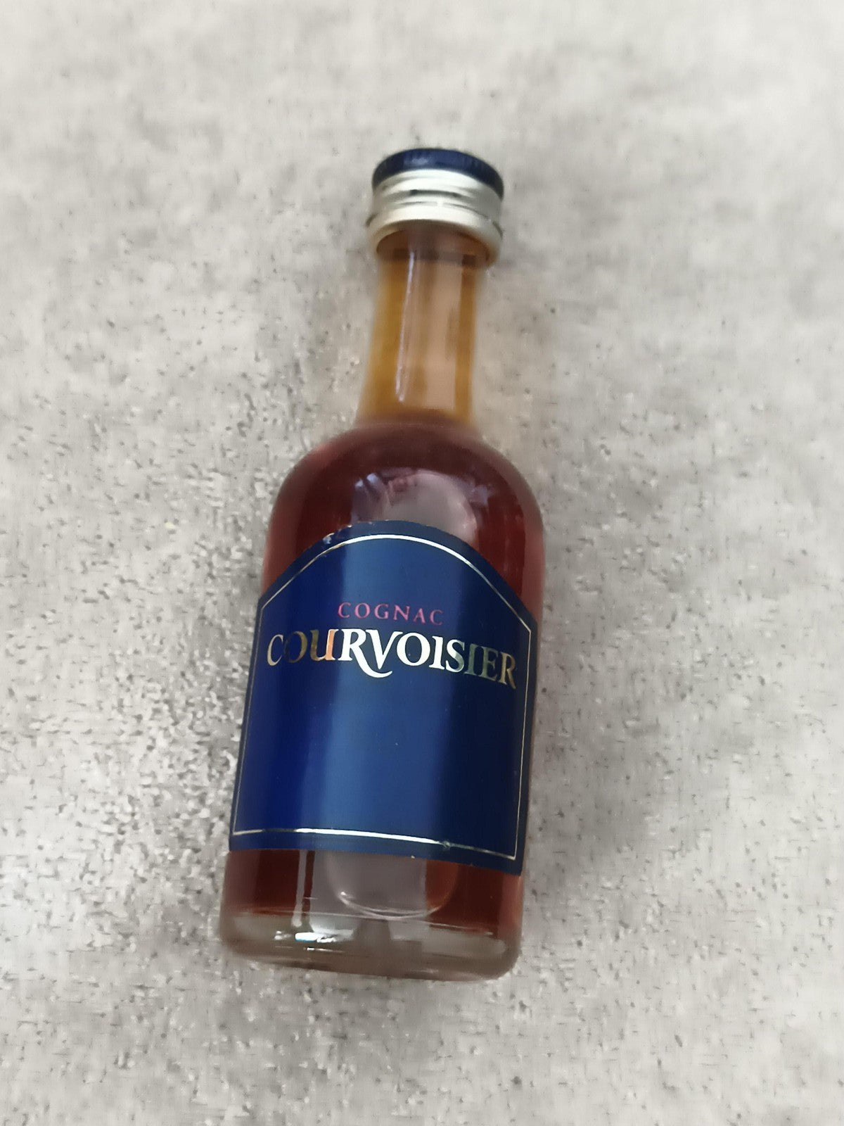 Mini-bouteille cognac Courvoisier partiellement remplie, étiquette bleue