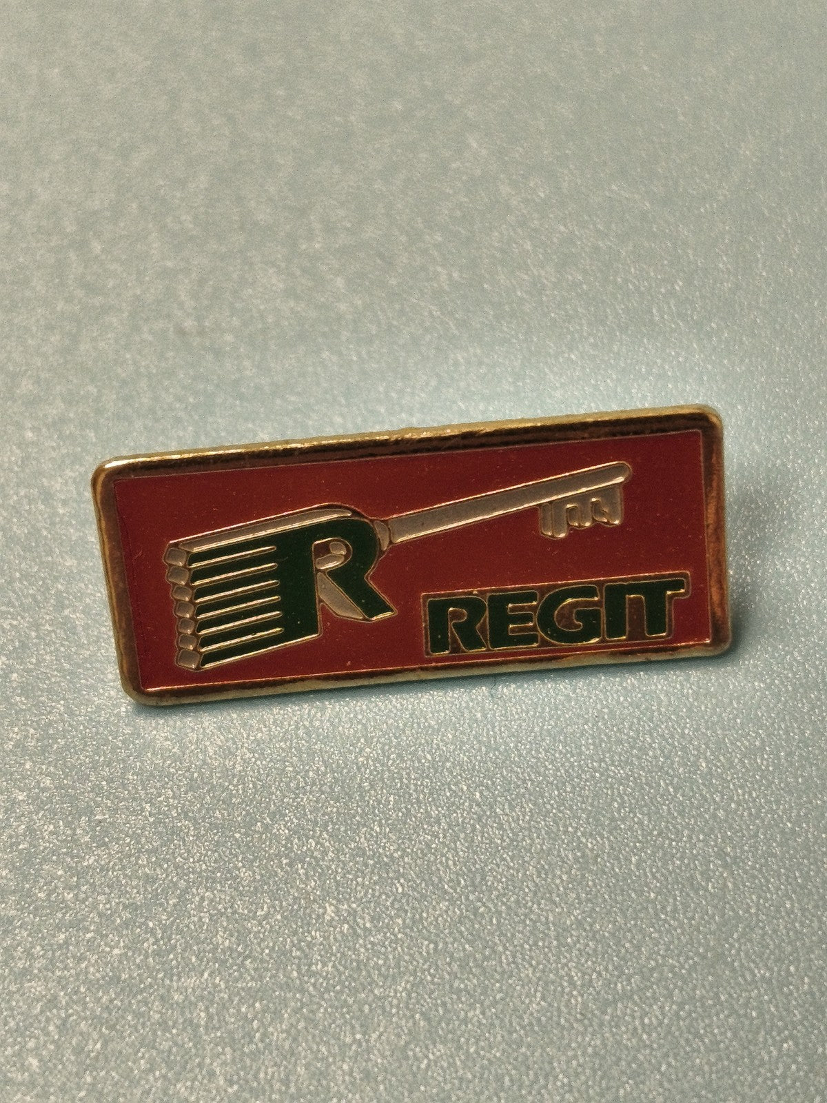 Vintage pin's publicitaire REGIT rectangulaire rouge logo clé collection