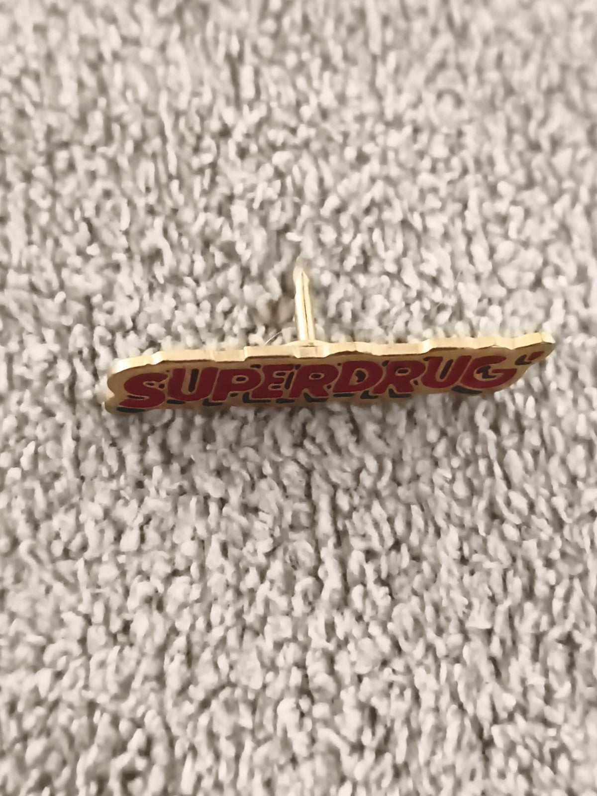 Pin's vintage SUPERDRUG lettrage rouge doré badge ancien (Ref 4)