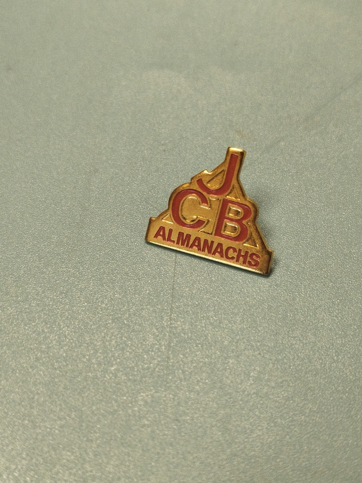 Vintage pin's JCB Almanachs doré rouge collection badge ancien (Ref 6)