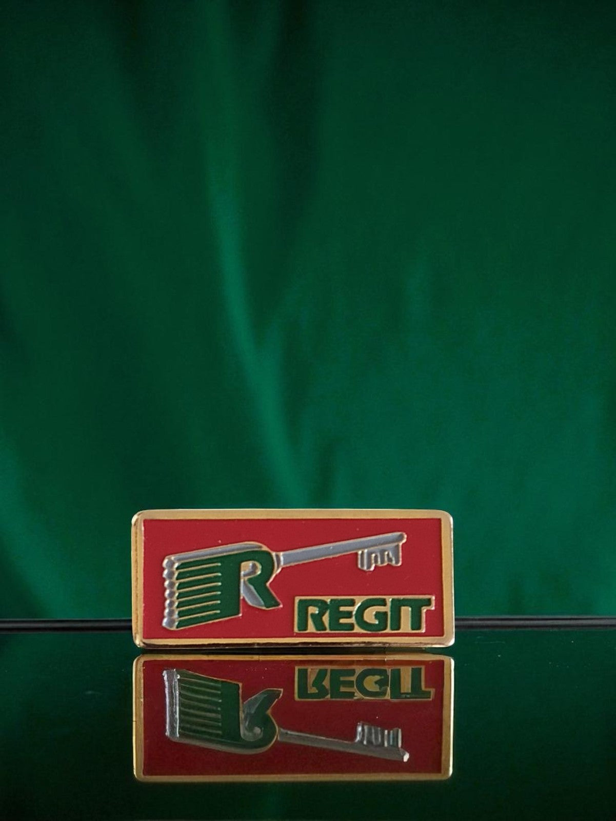 Pin's publicitaire vintage REGIT ancien, logo clé, rouge vert doré rétro