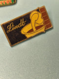 Pin's vintage Lindt chocolatier rectangulaire émaillé logo jaune collection