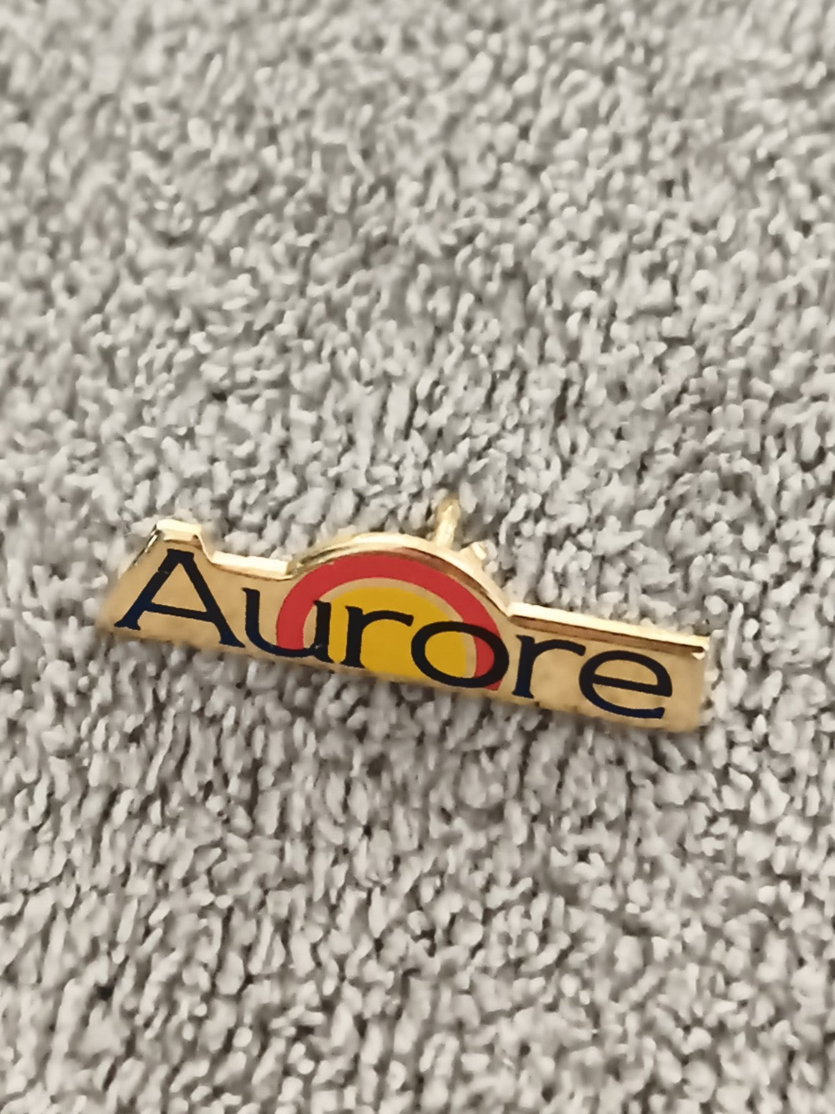 Pin's vintage Aurore logo arc jaune rouge, badge publicitaire années 90 (Ref 4)