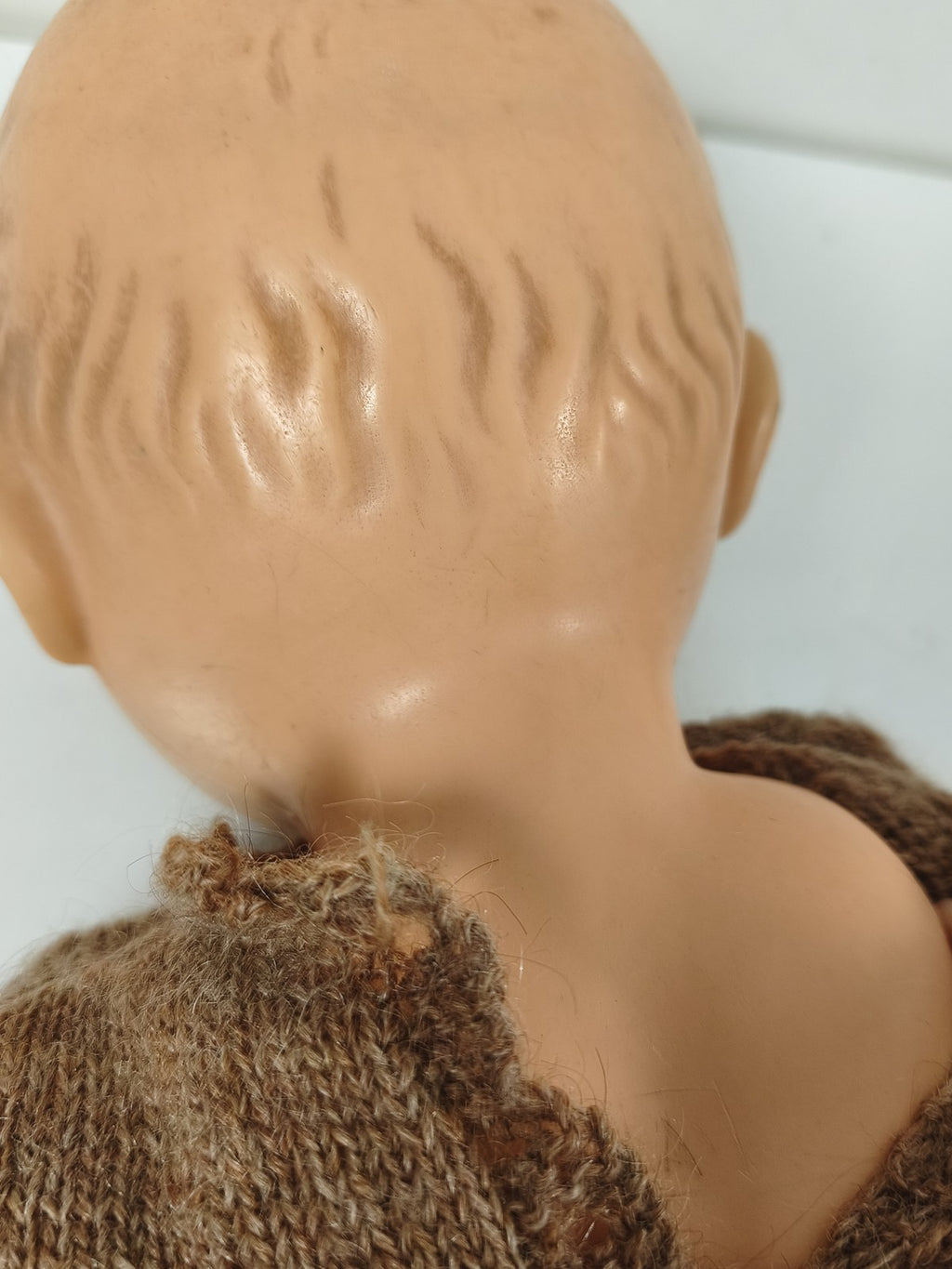 Poupée ancienne à yeux bleus, corps articulé, tenue tricotée brune