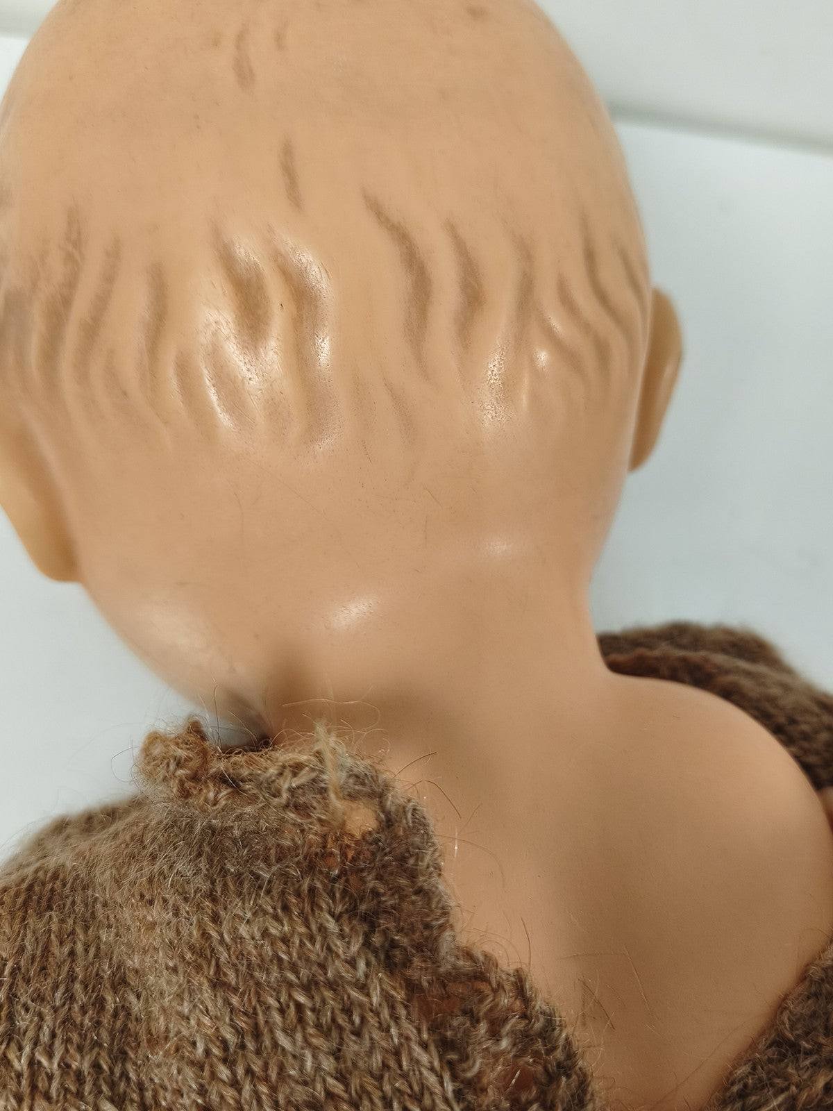 Poupée ancienne à yeux bleus, corps articulé, tenue tricotée brune