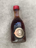 Miniature alcool bouteille décorative bouchon rouge partiellement remplie