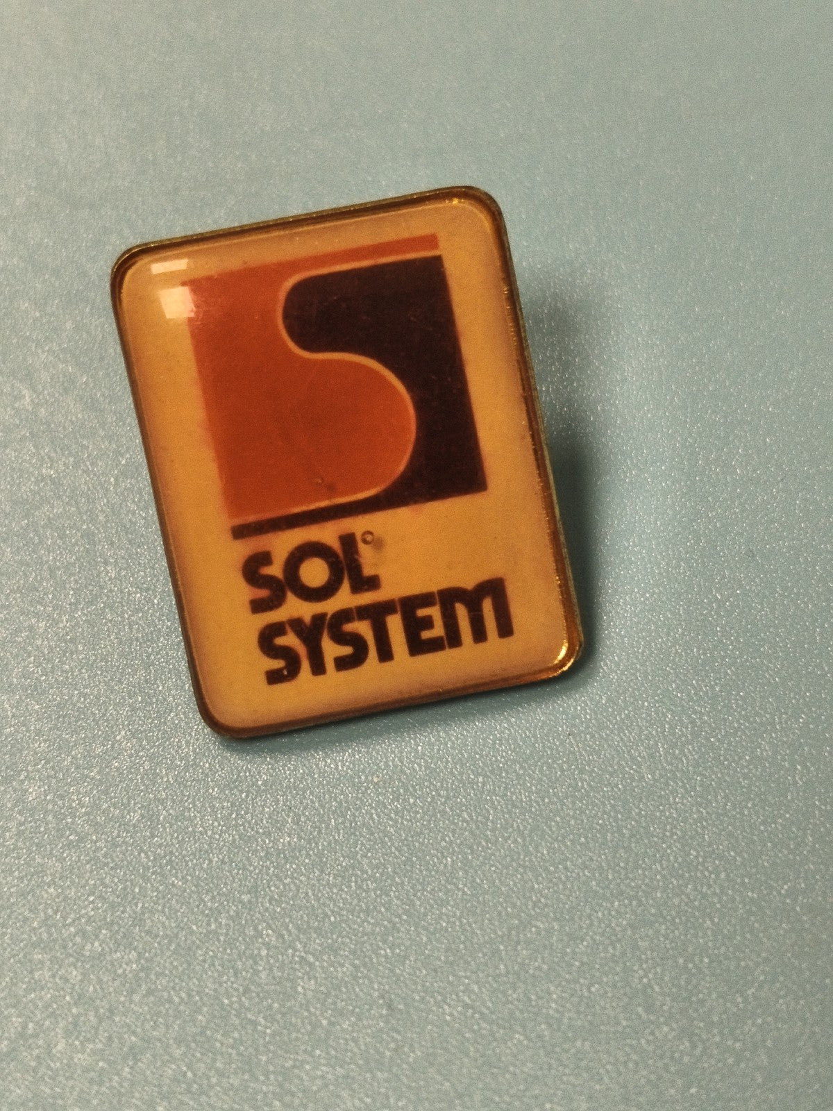 Vintage pin's Sol System rectangulaire logo rétro orange noir collection (Ref 14