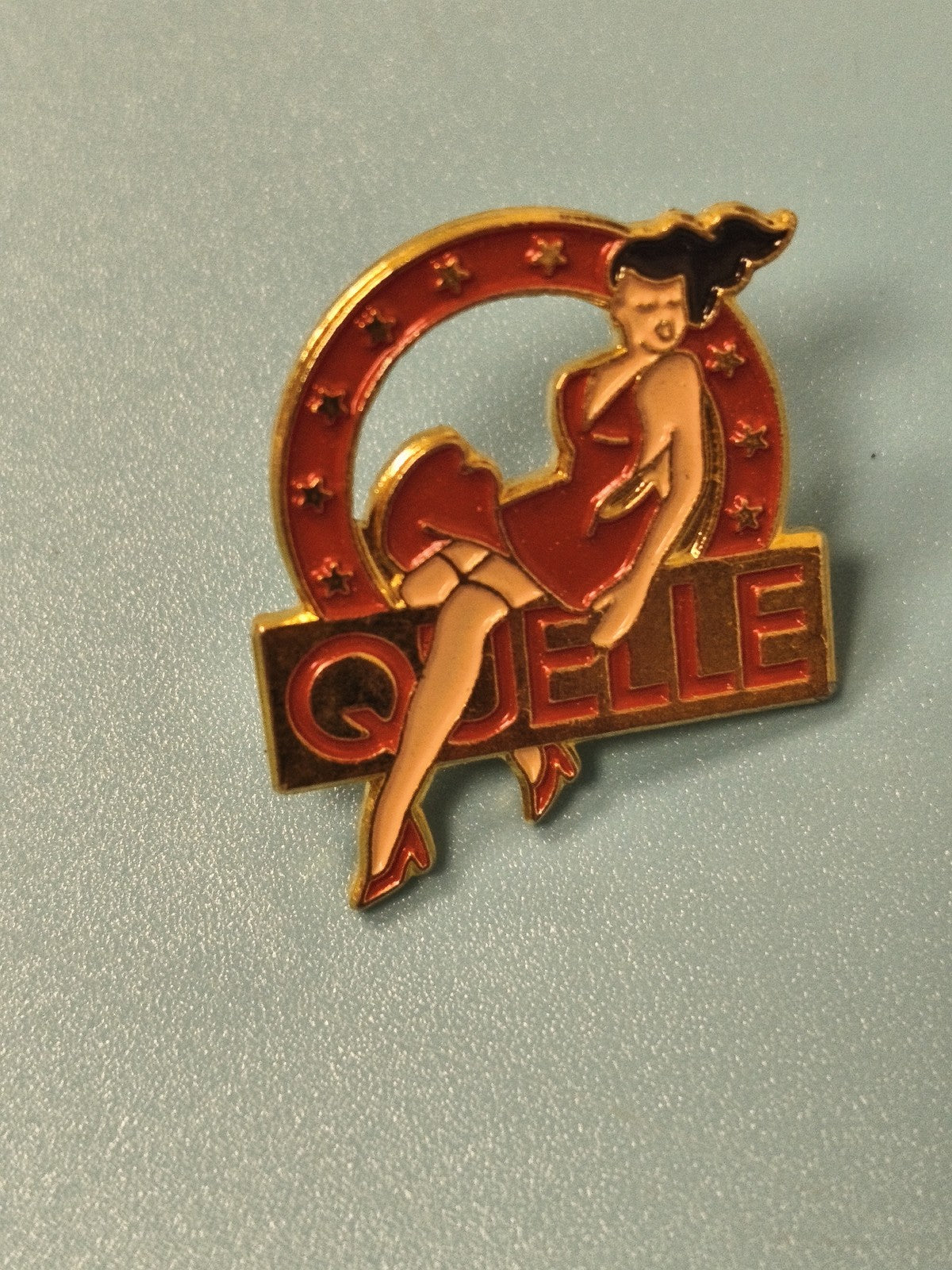 Vintage pin's publicitaire Quelle pin-up rouge, collection rétro (Ref 19)