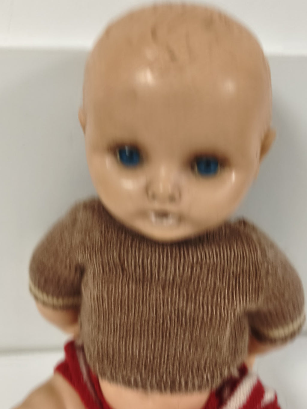 Poupée ancienne à yeux bleus, corps articulé, tenue tricotée brune