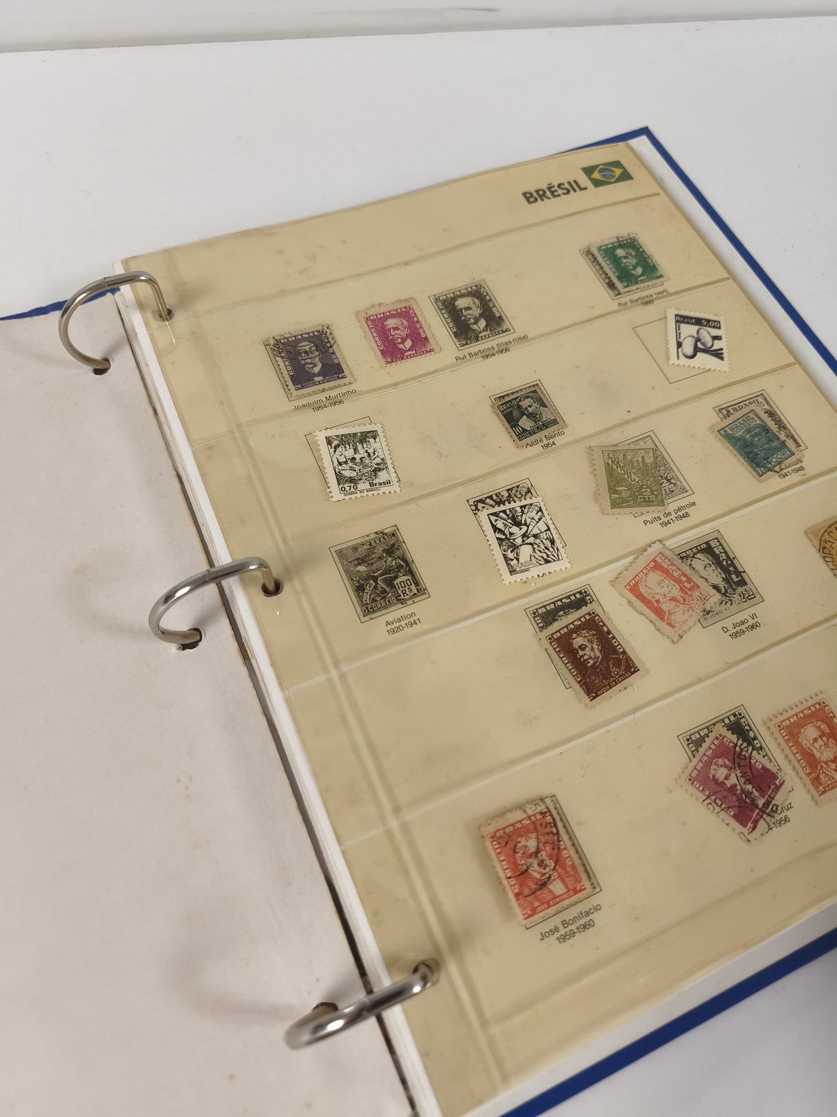 Classeur de timbres partiellement rempli, pages thématiques, couverture bleue