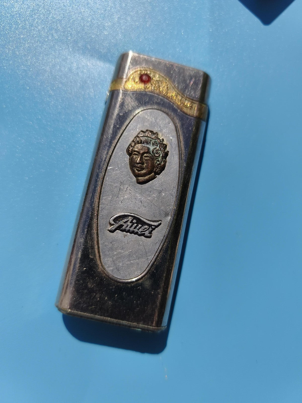 Ancien briquet publicitaire Jivet, décor visage, métal argenté, à restaurer