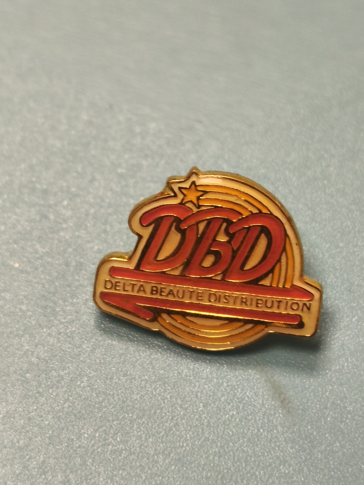 Pin's vintage DBD Delta Beauté Distribution doré rouge logo étoile collection