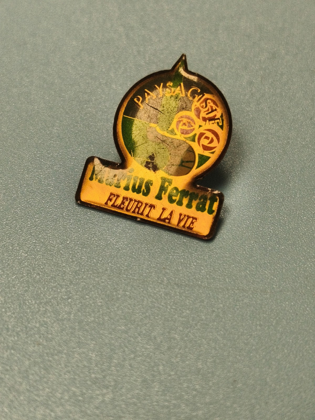 Vintage pin's publicitaire Marius Ferrat paysagiste vert jaune ancien (Ref 14)