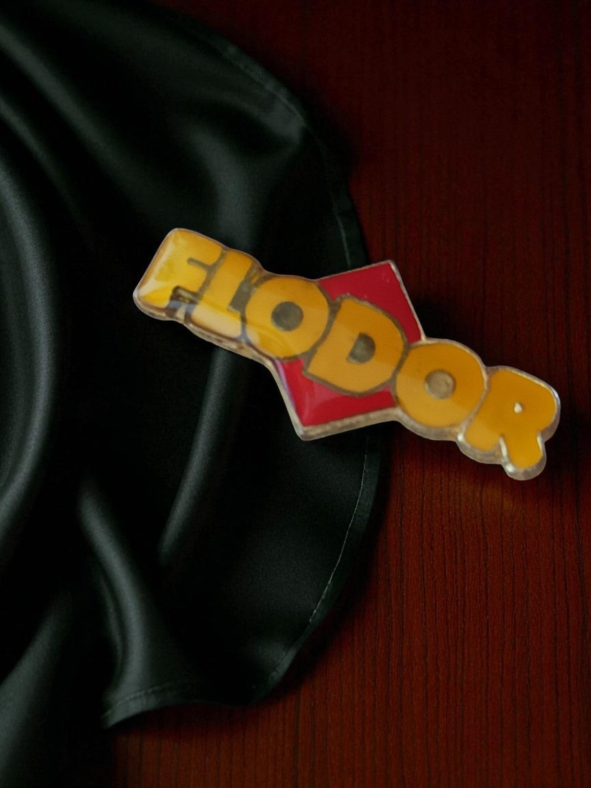 Pin's publicitaire vintage FLODOR en émail, logo jaune rouge, rare badge ancien