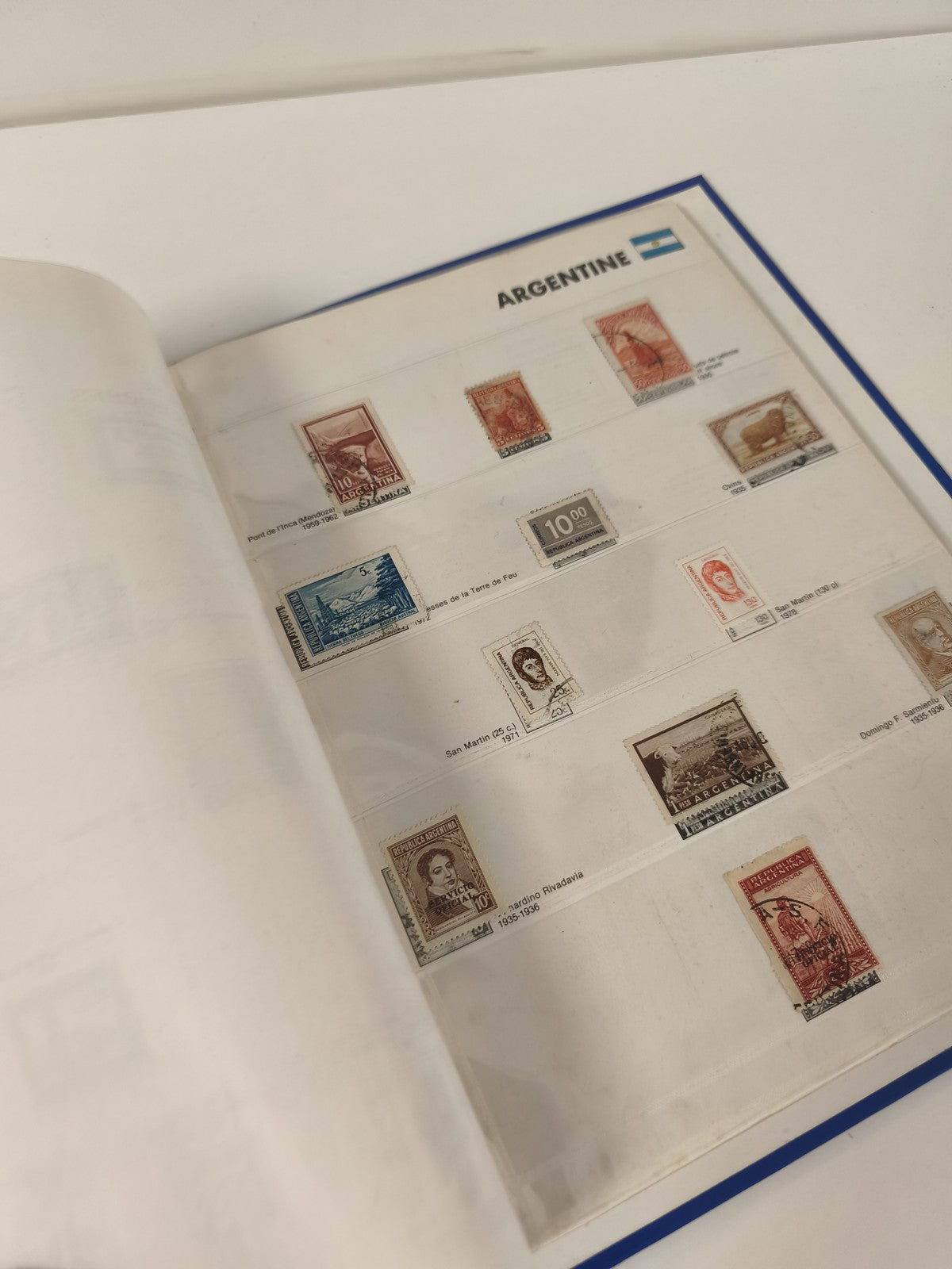 Classeur de timbres partiellement rempli, pages thématiques, couverture bleue