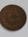 Médaille ronde décor gravé, aspect bronze, motif géométrique ethnique