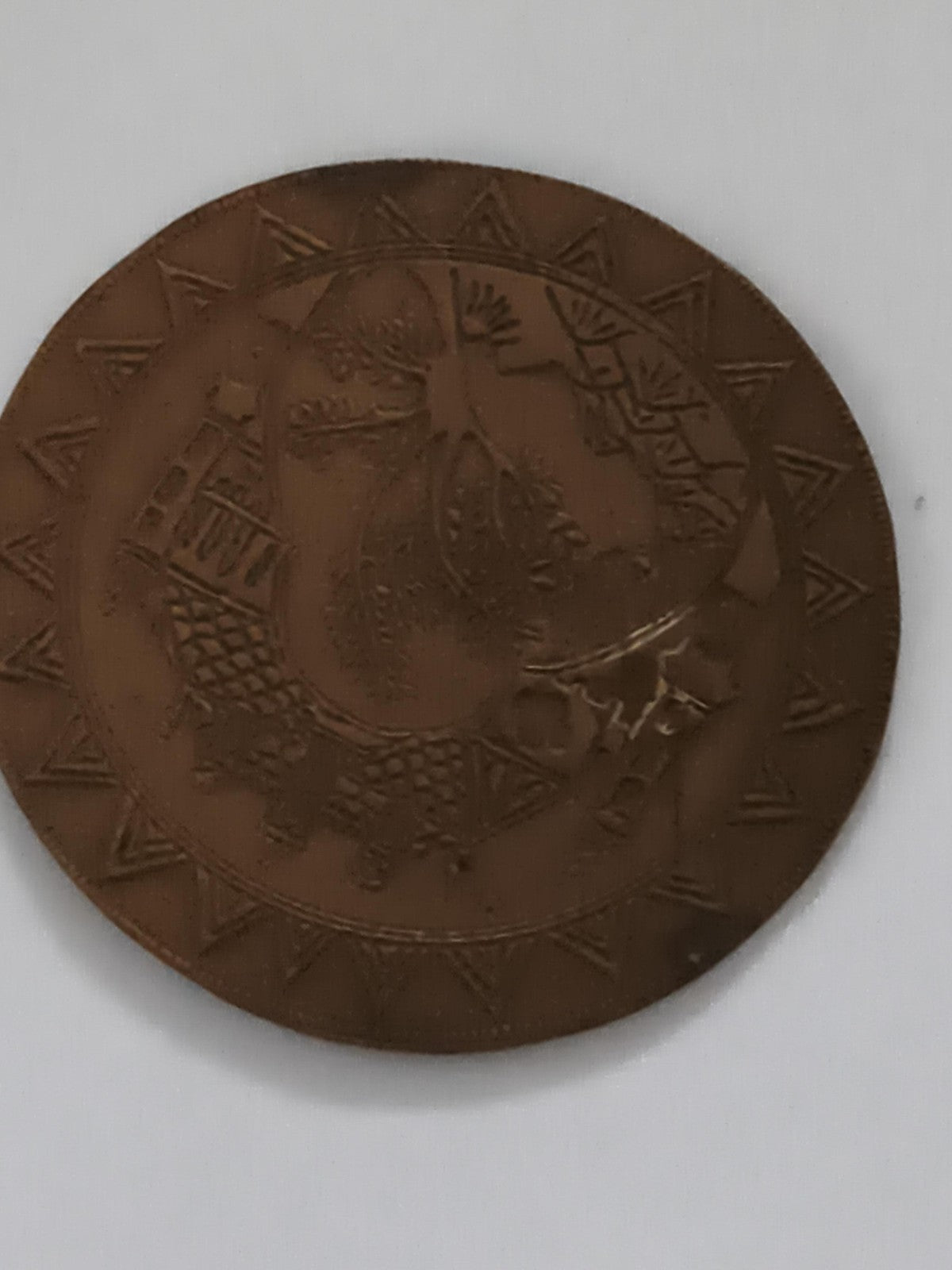Médaille ronde décor gravé, aspect bronze, motif géométrique ethnique