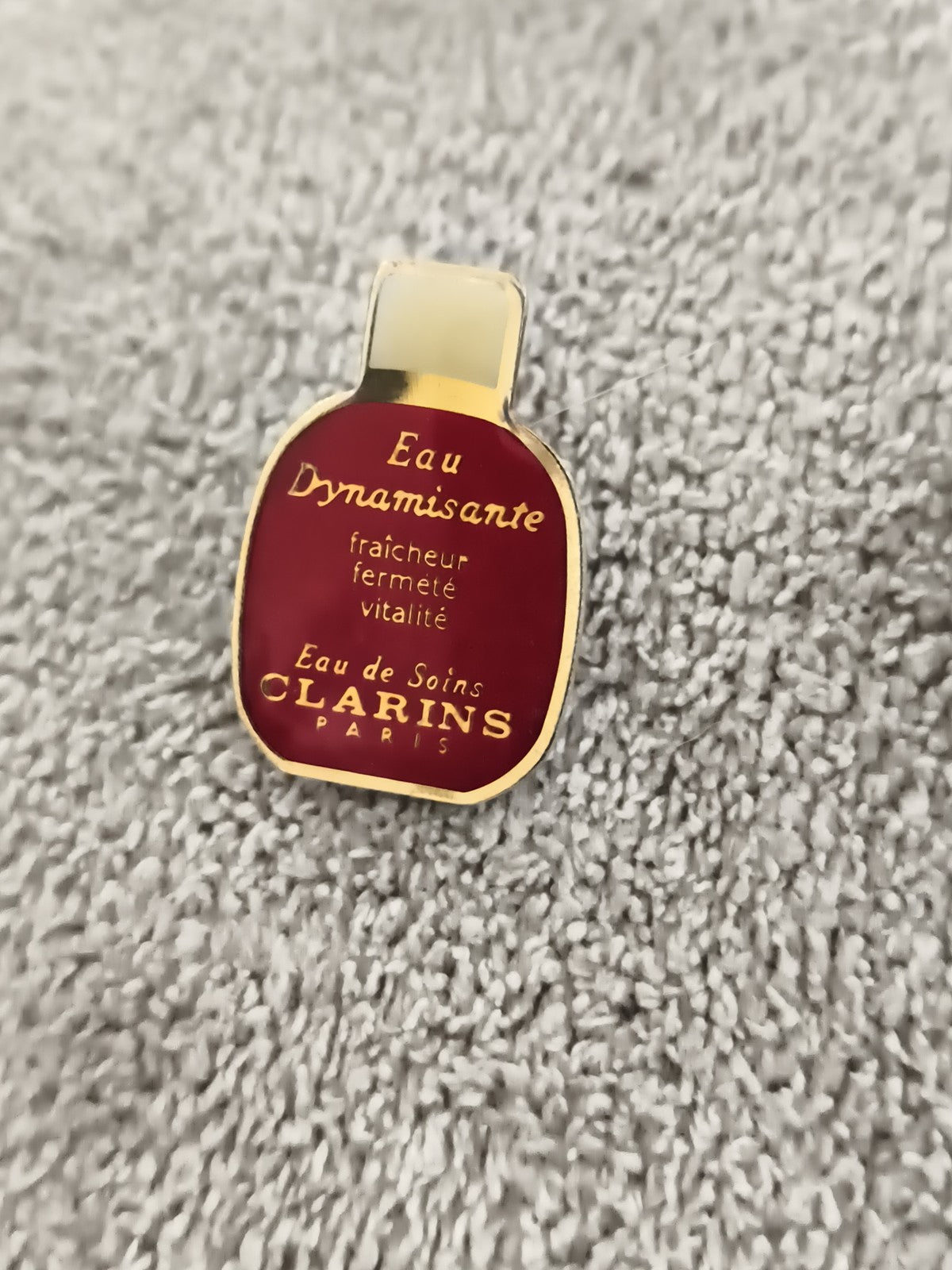 Pin's vintage Clarins Eau Dynamisante rouge or, badge parfum ancien (Ref 5)
