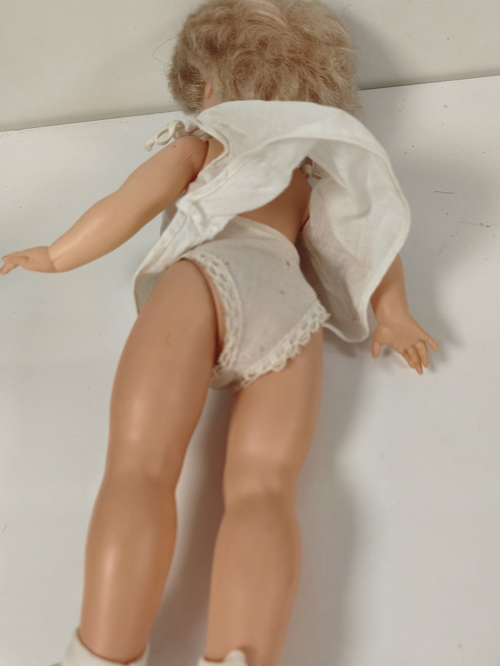 Ancienne poupée blonde aux yeux bleus, robe blanche et corps articulé