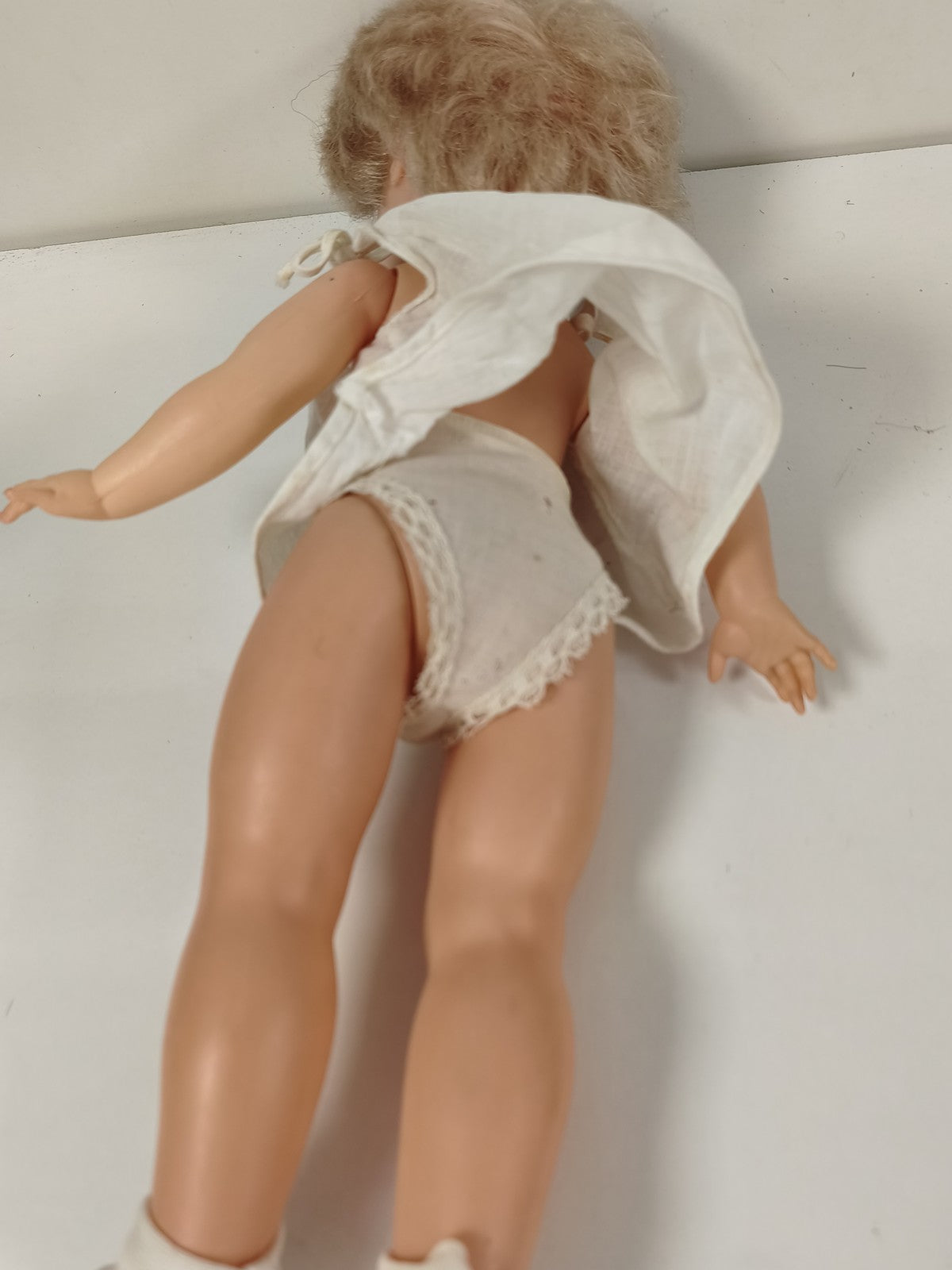 Ancienne poupée blonde aux yeux bleus, robe blanche et corps articulé
